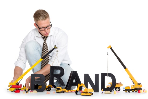 Brand start up: Businessman building brand-word.